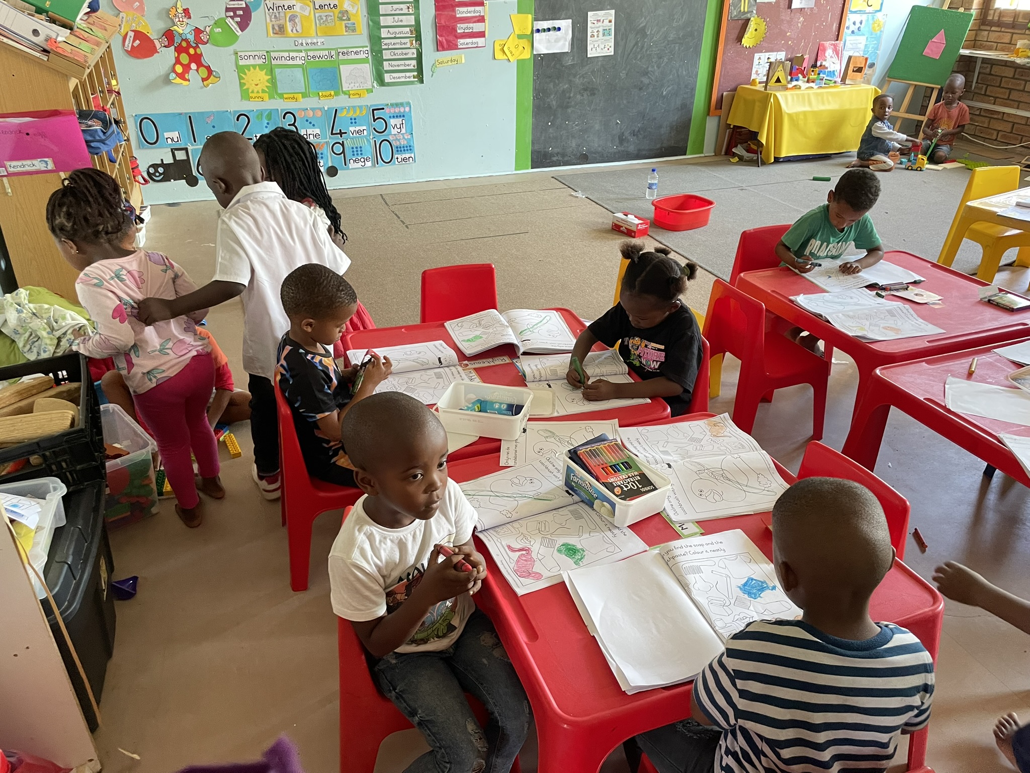 Kinder im Kindergarten an Tischen am lernen.