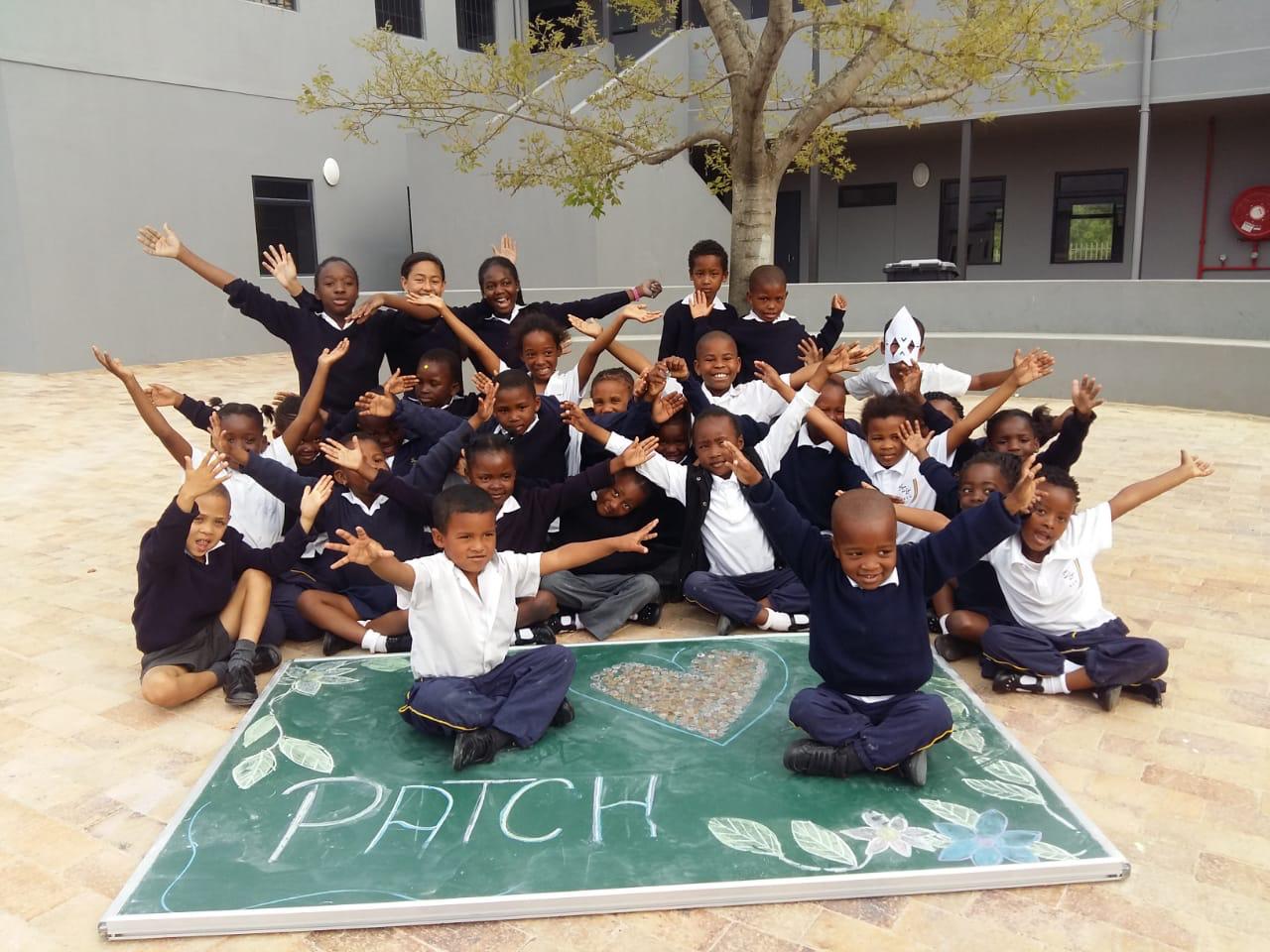 Kinder im Schulhof mit ausgestreckten Armen am Lachen.